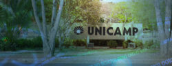 Placa da Unicamp com sobreposição em azul com ícones de ciência
